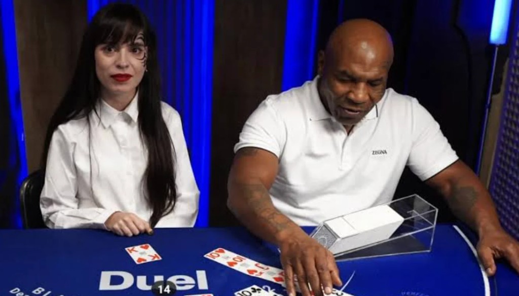 Mike Tyson dealing at the blue Duel blackjack table beside a croupier